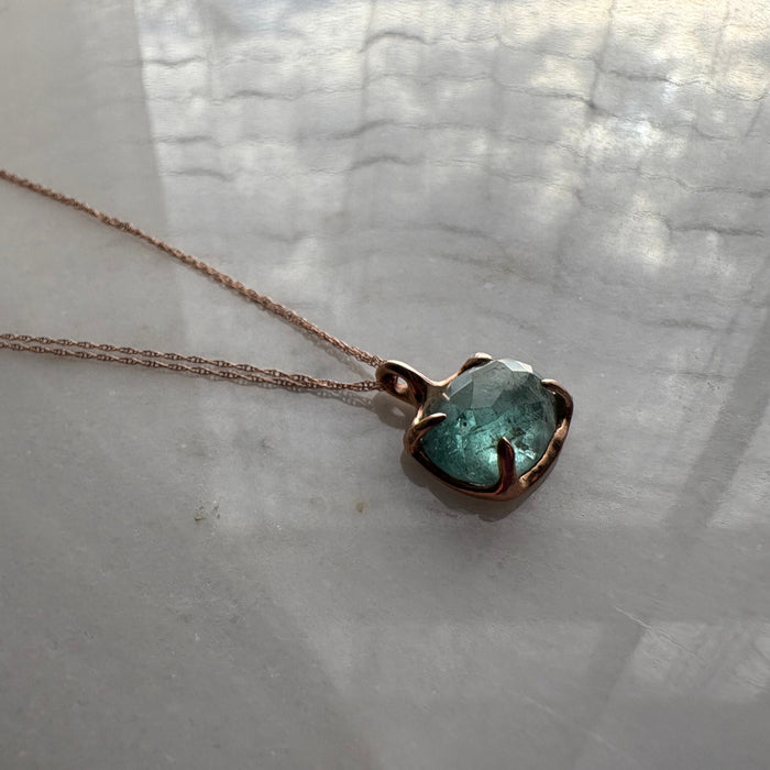 Necklace with a green gemstone pendant on a light background